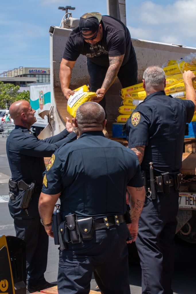 Man handing bags of rice to police officers during food drive.