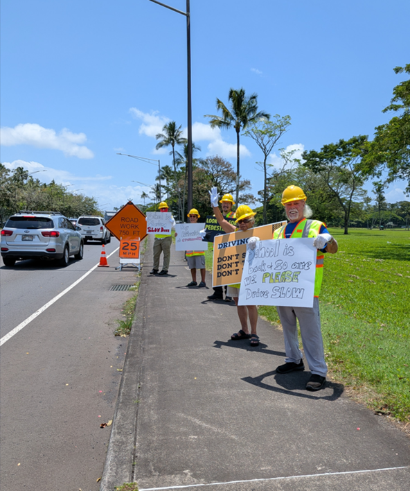 People sign waving on sidewalk for traffic safety awareness.