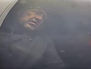 Reflection of man in ATM window. Man is a theft suspect sought by police.
