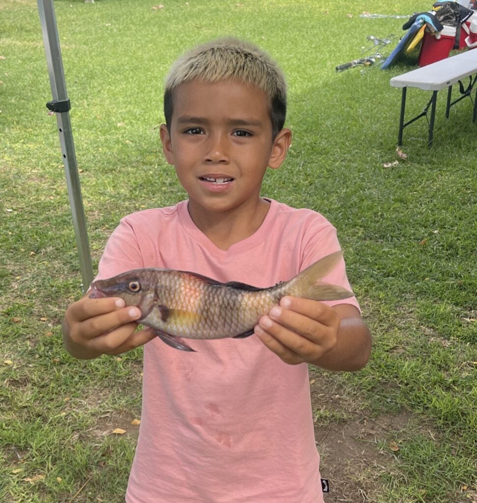 Boy in pink shirt holding fish
