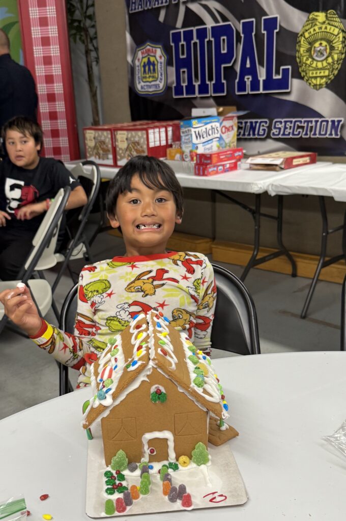 Boy decorating gingerbread house.