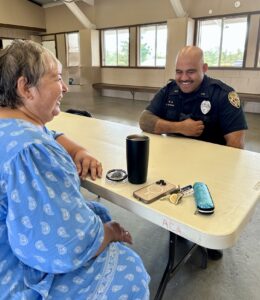 CPO Terrace Scanlan laughing with woman while seated at table. 