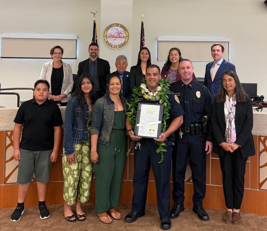 Kaʻū Police Captain Pernell Hanoa holding Haweo award standing with his family and County Council members.