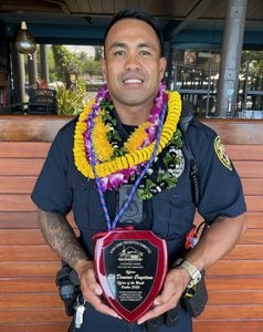 Officer Cayetano holding Officer of the Month Award.