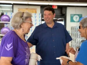 Police Chief smiling and laughing with two elderly women at community event.