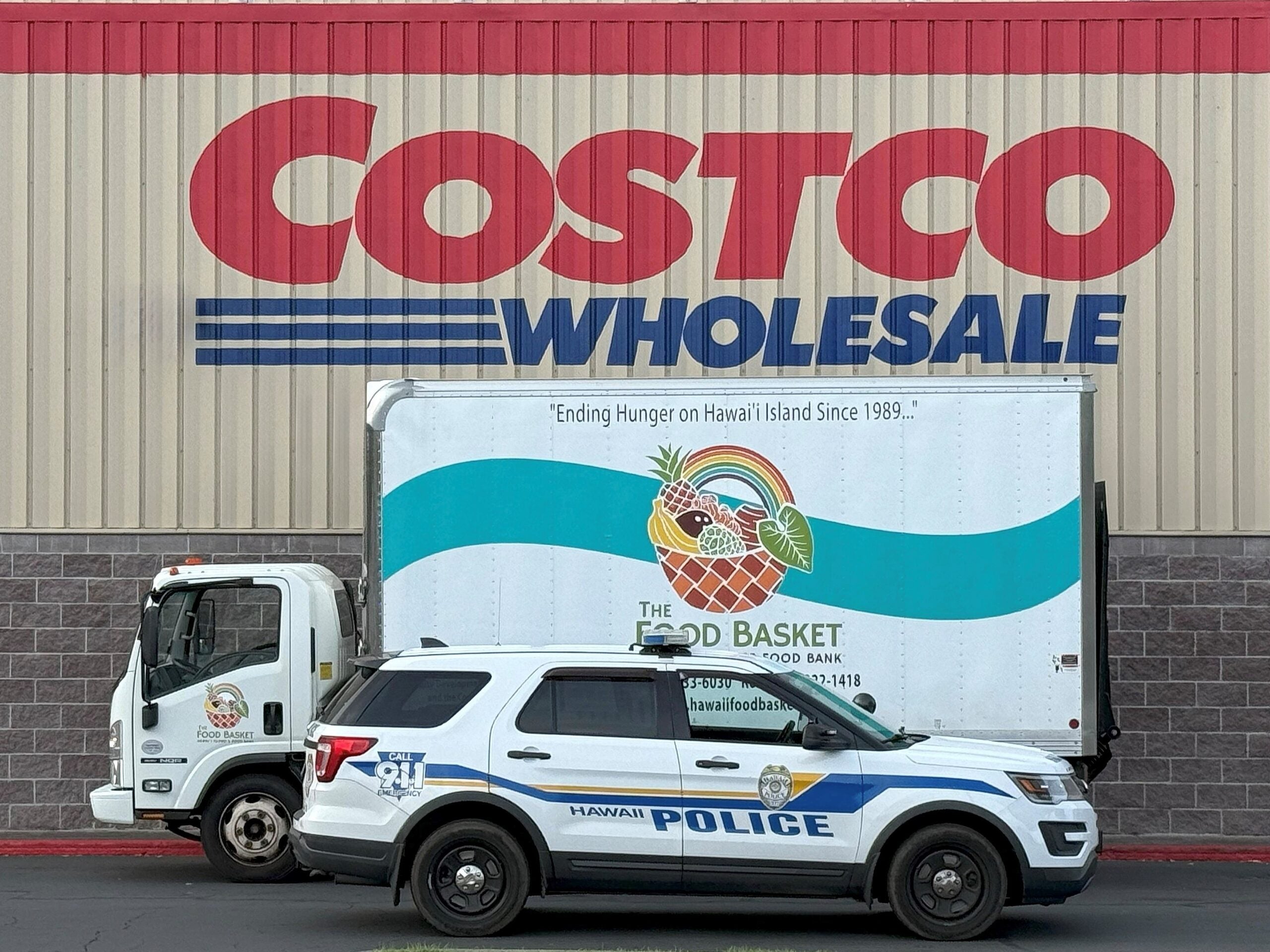 Police Cruiser and large box truck from the Food Bank parked in front of Costco.