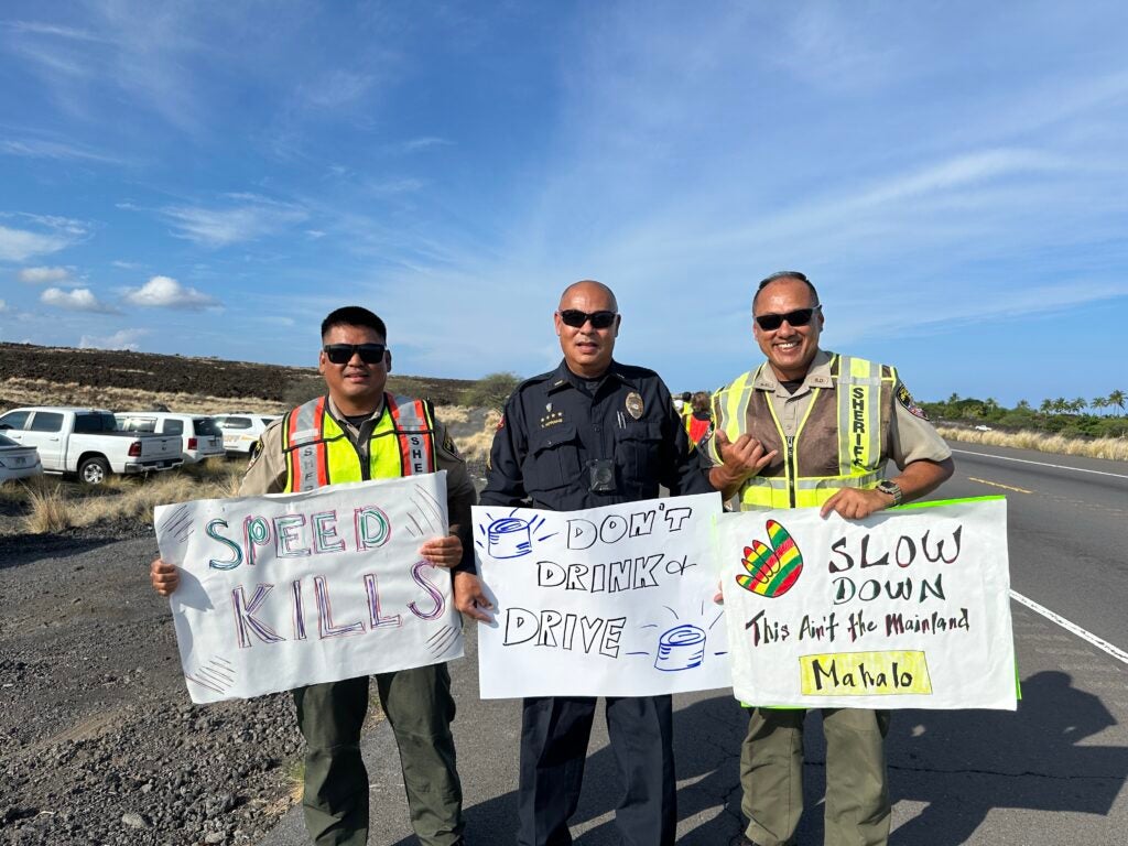 Dept. of Law Enforcement Sheriffs with Sergeant Thomas Koyanagi holding traffic safety signs during sign waving event in October 2025.