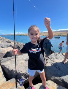 Girl holding fish by ocean. 