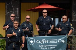 Five police officers standing behind Coffee With a Cop banner at Caffe Florian.