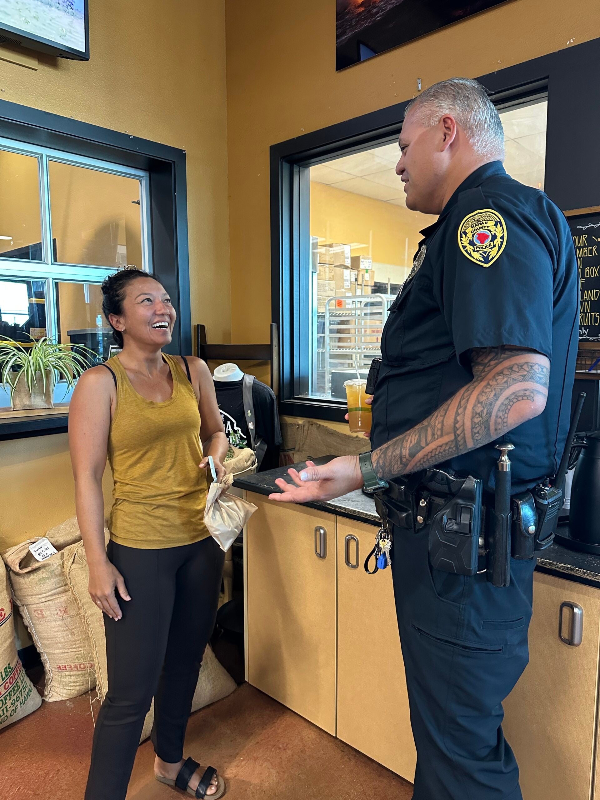 Officer talking with a woman inside cafe at Coffee With a Cop.