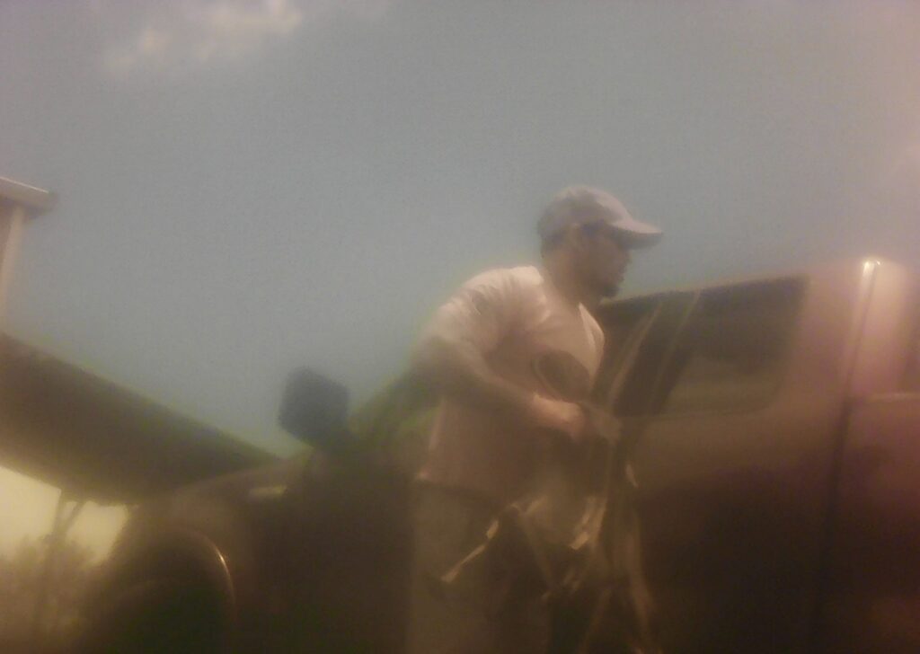 fuzzy photo of Kona burglary suspect #1 - man standing next to open driver's door of pick up truck.