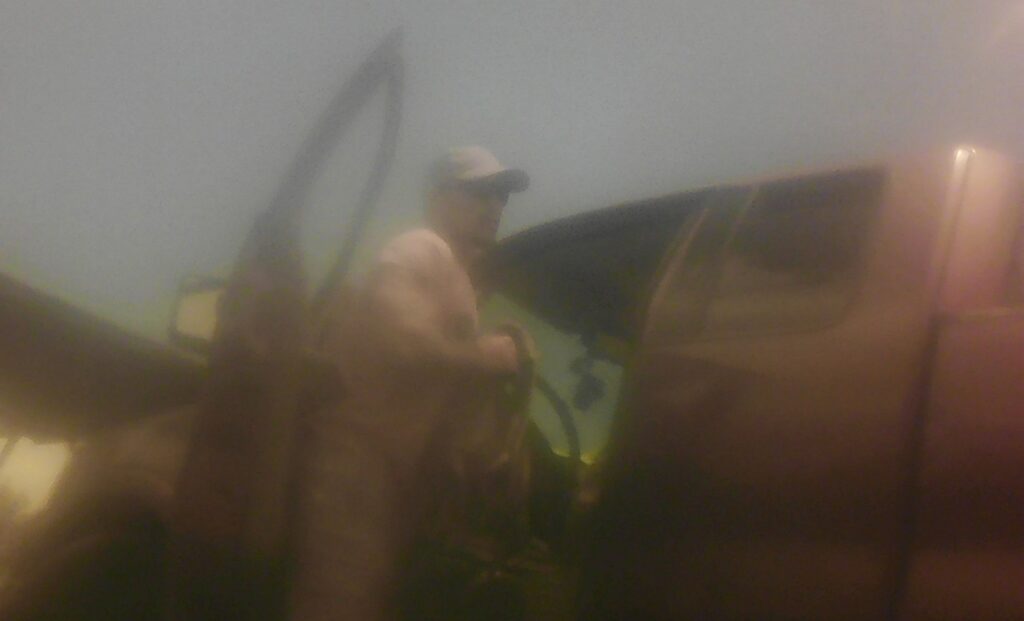 fuzzy photo of Kona burglary suspect #1 - man standing next to open driver's door of pick up truck.