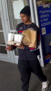 Man walking out of storing carrying tray of fast-food drinks who is a person of interest in a motorcycle theft case. 