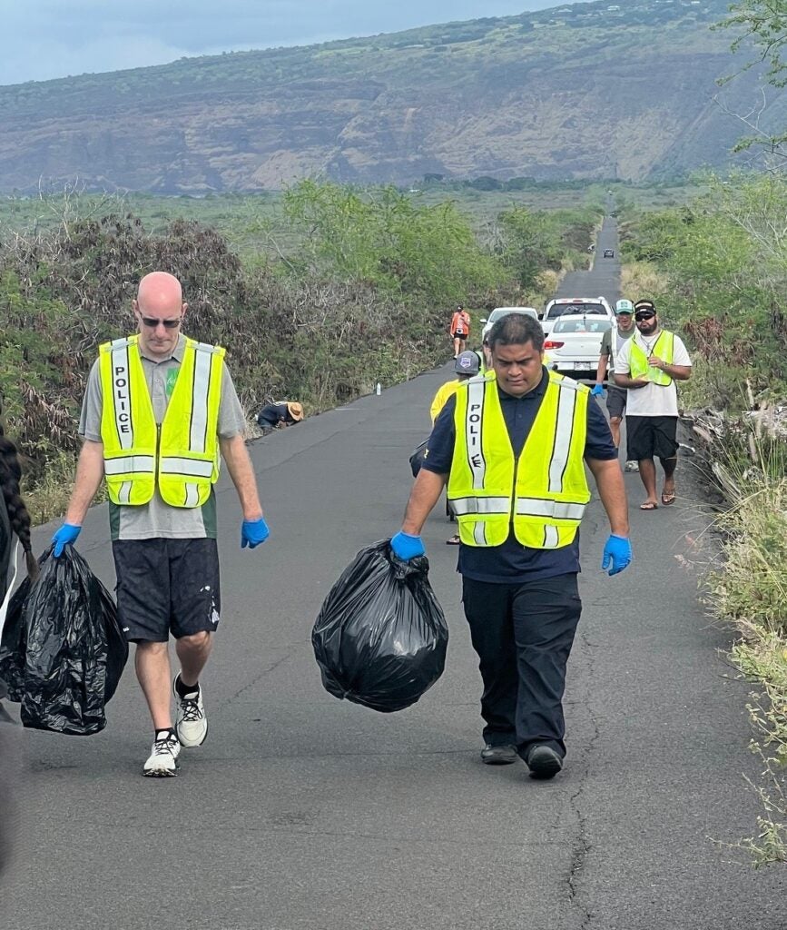 LT Mansur and Officer Meno carry bags of trash during community clean-up.