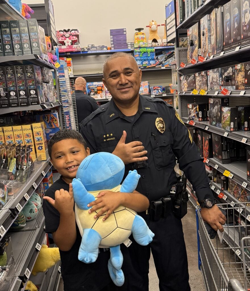 Sergeant Wyattlane Nahale with young boy during Shop With a Cop.