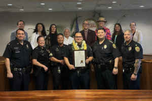Officer Barto holding his Haweo award standing with police senior commanders and members of Hawaii County Council.  