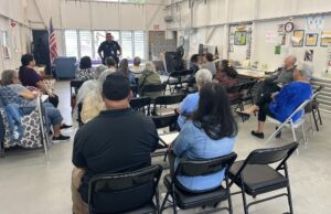 Officer Cardines talking to group of seniors in a community room. 
