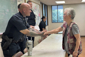 Picture of police officer shaking elderly woman’s hand at Kupuna Watch community meeting.