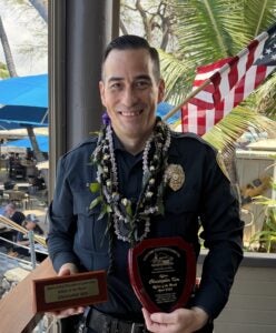 Kona Patrol Officer Christopher Kim holding his Officer of the Month for April 2026 by the Kona Crime Prevention Committee. 