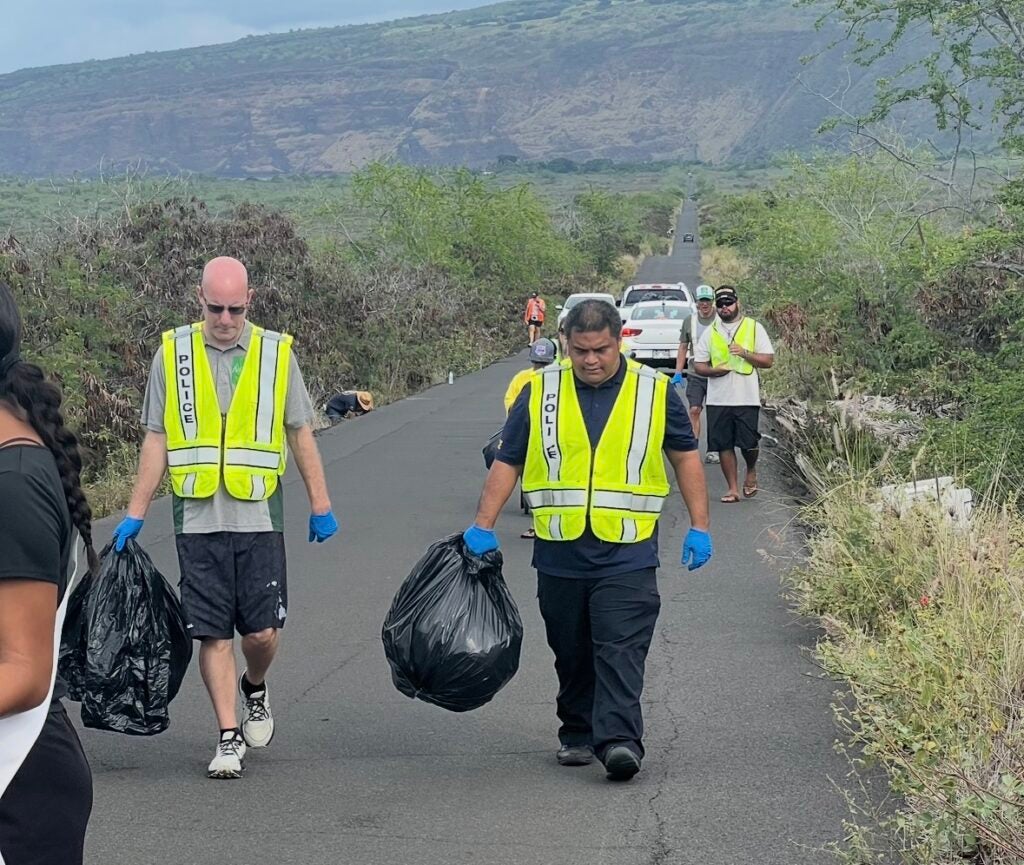 Two officers carrying bags of trash during cleanup