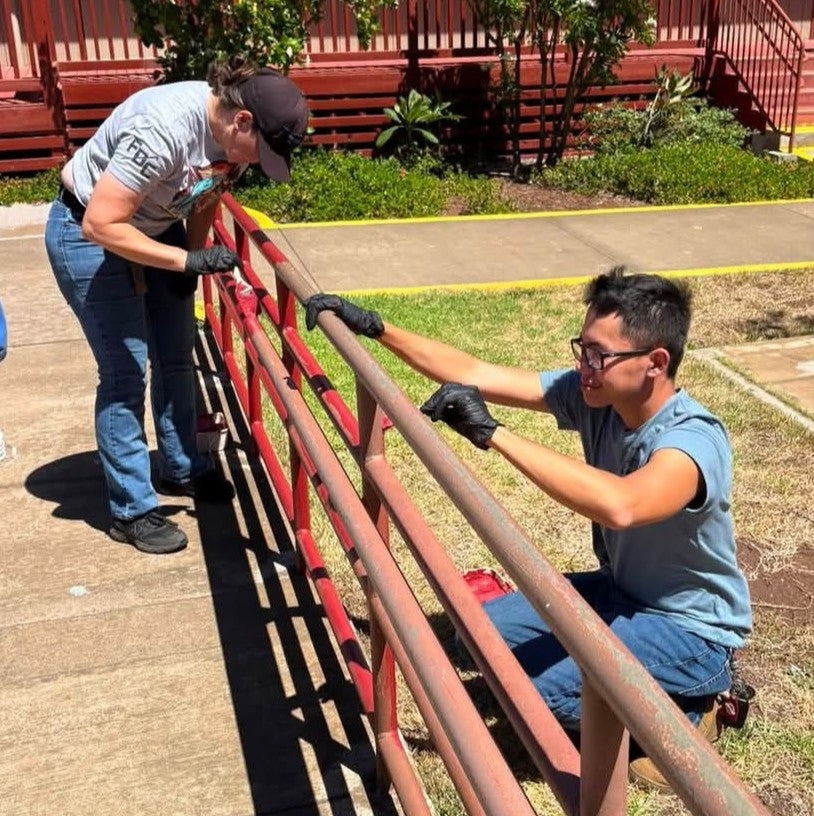 Woman and grown son painting railing at school beautification project