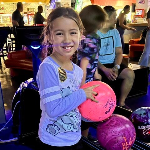 girl holding pink bowling ball
