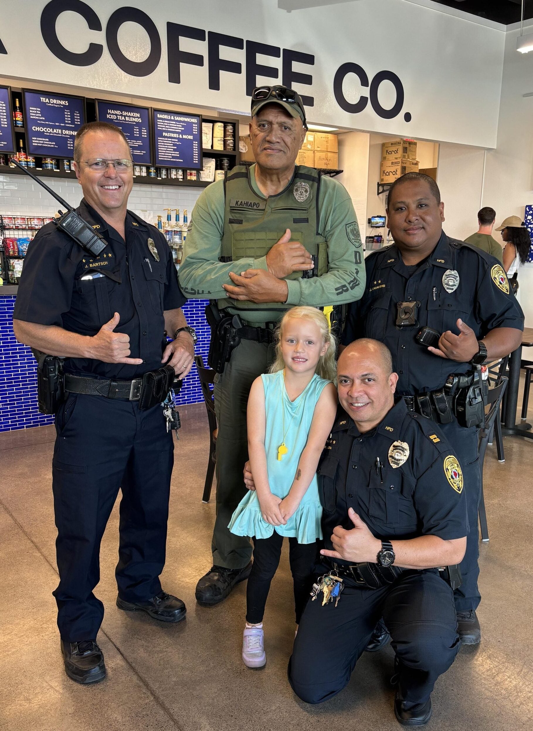 Three officers posing with a old man and a young girl at Kohala Coffee.