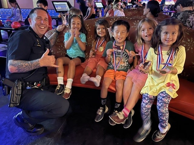 officer with kids wearing medals at bowling event